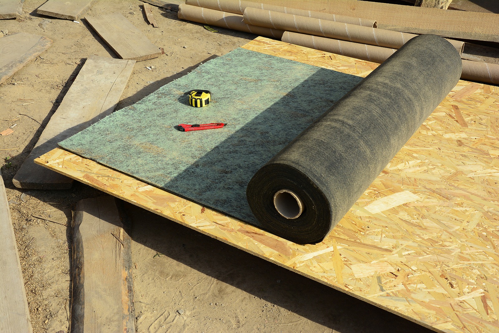 A close-up on bitumen paper roofing felt, underlayment, water-resistant and waterproof barrier material unrolled on the roof deck while roofing construction.