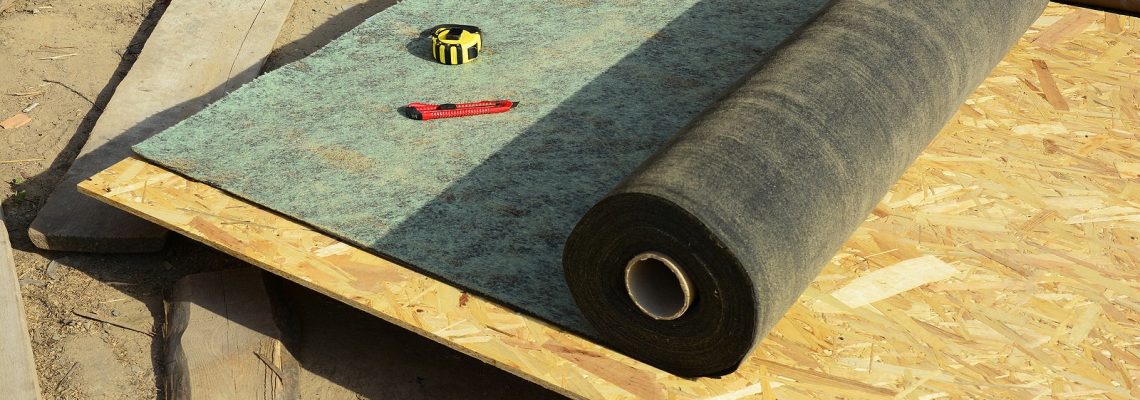 A close-up on bitumen paper roofing felt, underlayment, water-resistant and waterproof barrier material unrolled on the roof deck while roofing construction.